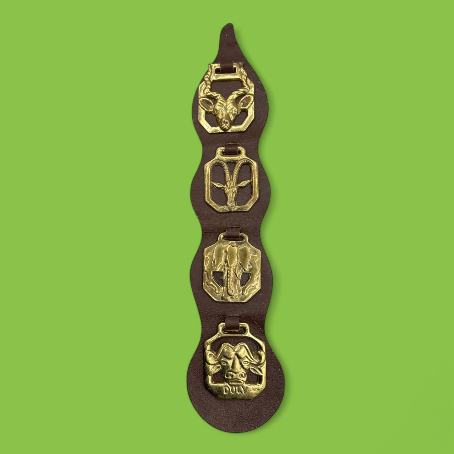 Brass horse decorations on leather strap showcasing African animals like elephants and antelopes. Horse, brass, African animals.