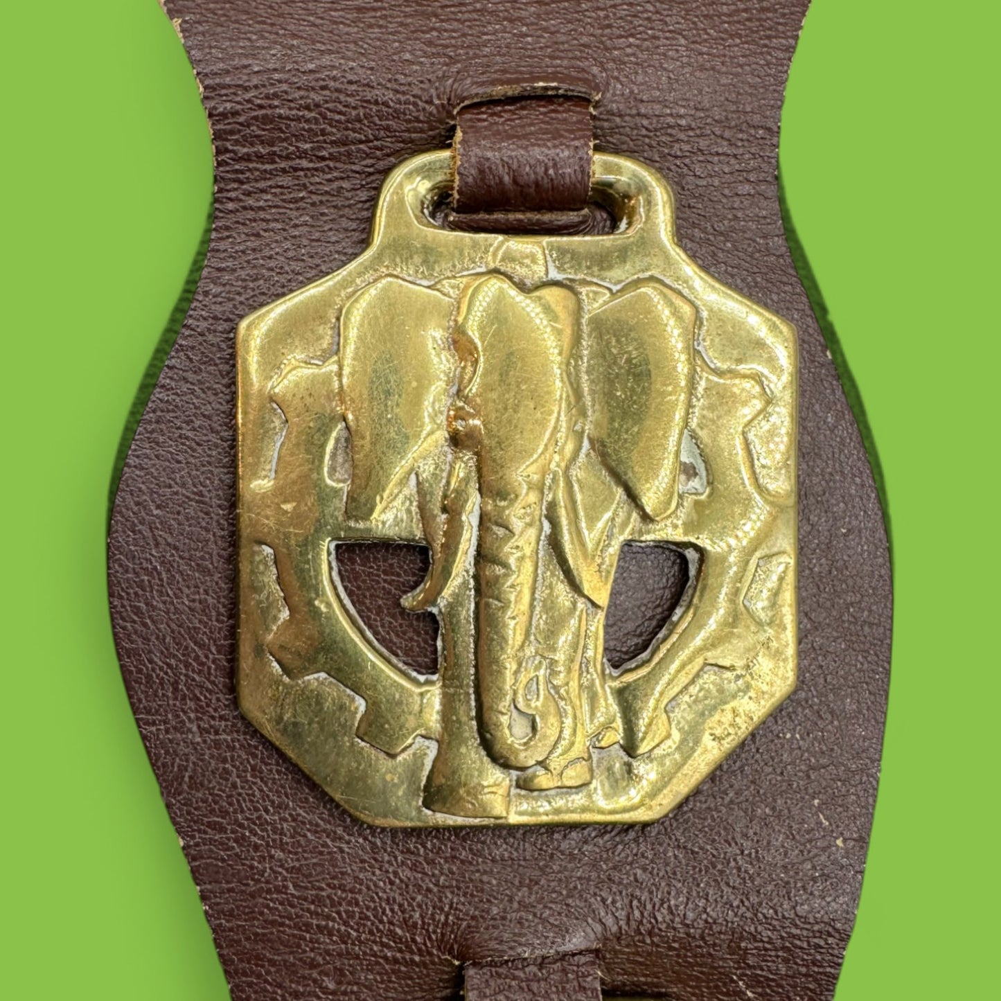 Brass horse ornament on leather strap, featuring African animals like elephants and buffalo. Ideal for collectors.