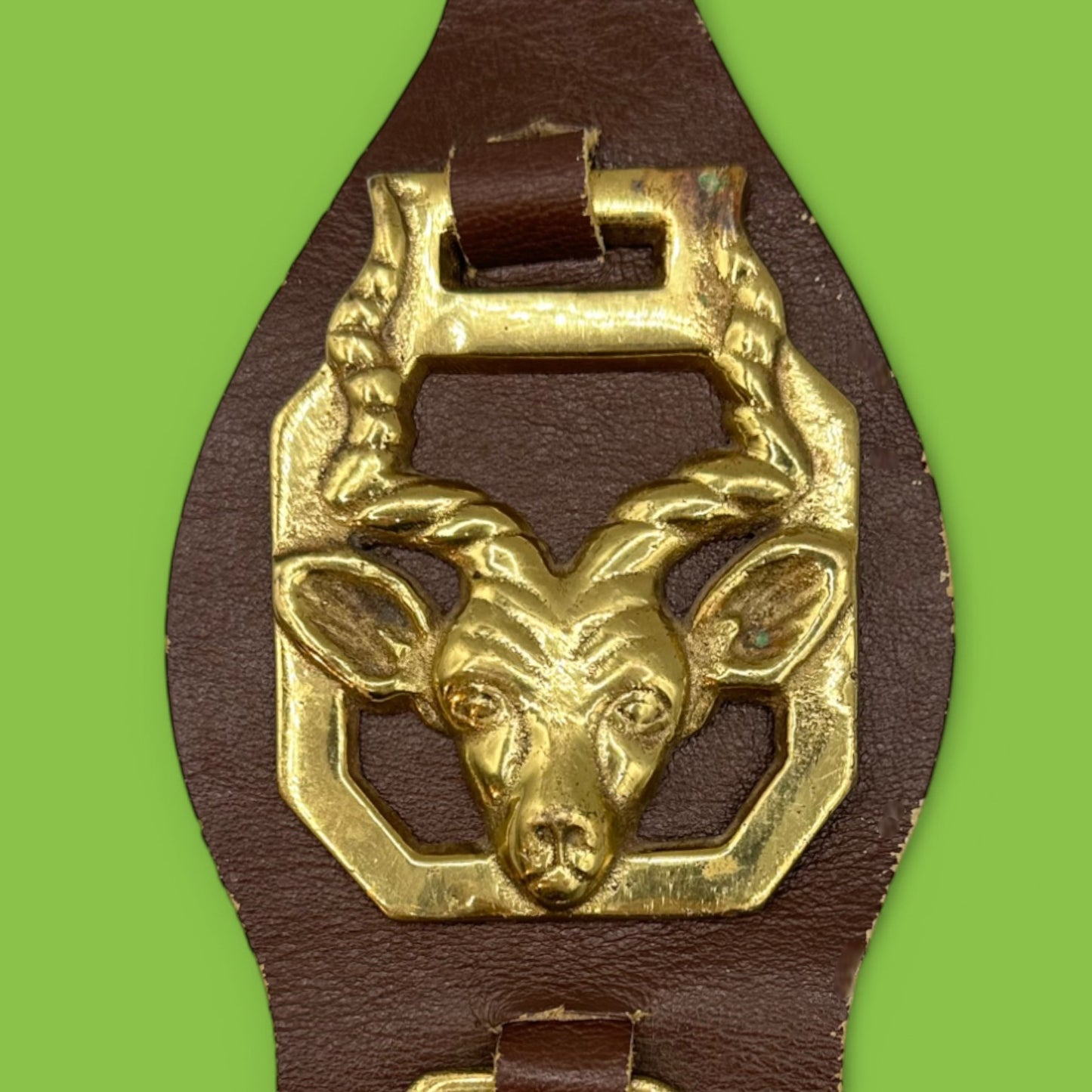 Brass horse adornment on leather strap featuring African animals like antelope and elephant, perfect for decor.