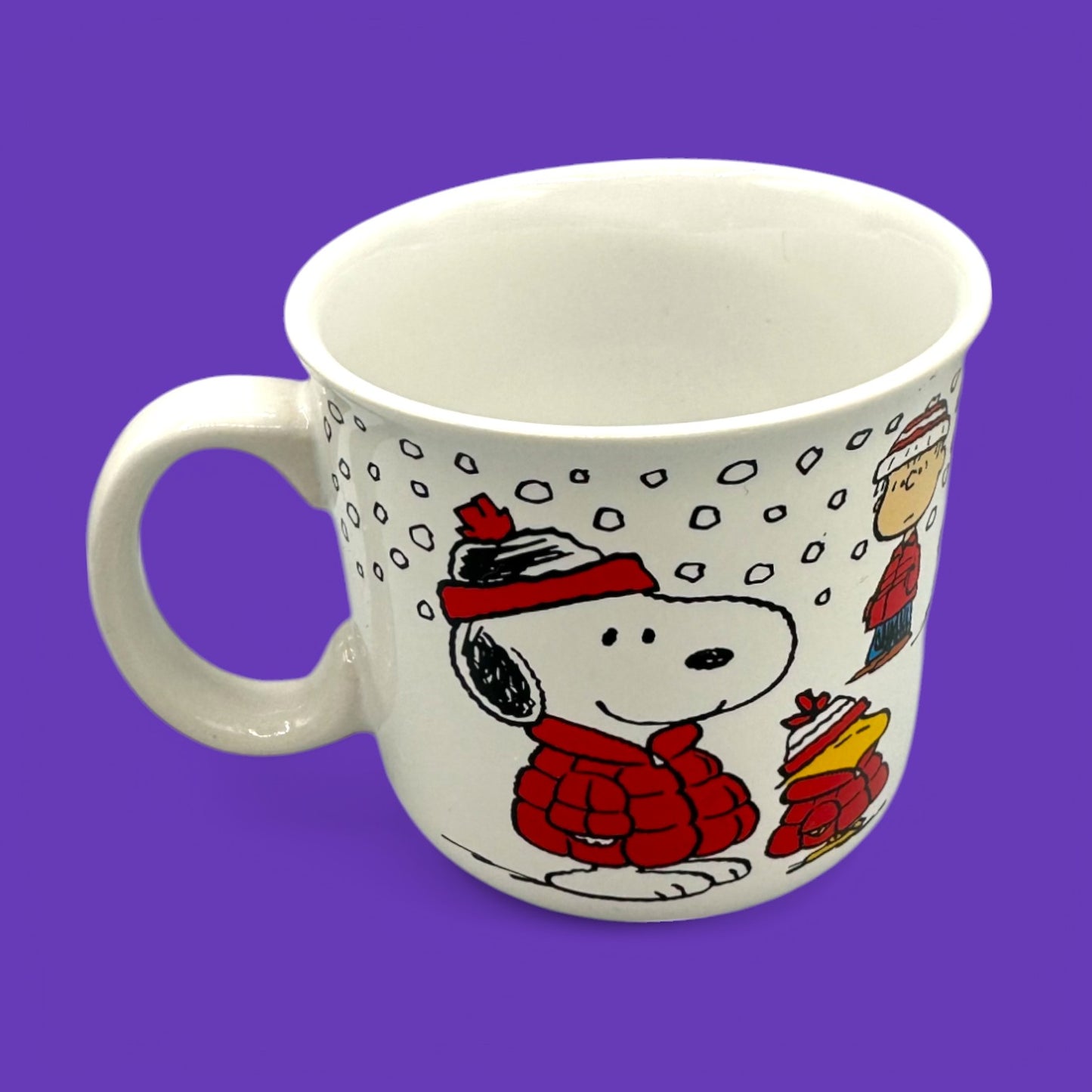 Cozy up with this Vintage Peanuts Snoopy winter mug featuring Snoopy, Woodstock, and Charlie Brown in festive attire.
