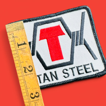 Vintage 1990's Titan Steel Embroidered Patch featuring a red 'T' on a white background, measuring 2.5" x 3.5".