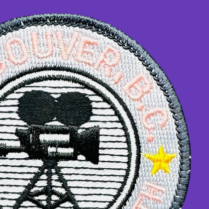 Vancouver BC, Hollywood North Embroidered Patch, 1980's with pink lettering and film camera silhouette on grey background.