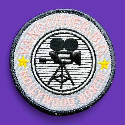 Vancouver BC, Hollywood North Embroidered Patch, 1980's features pink lettering and a film camera design on a grey background.