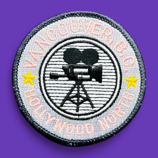 Vancouver BC, Hollywood North Embroidered Patch, 1980's features pink lettering and a film camera design on a grey background.