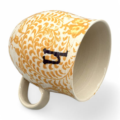Curved Anthropologie mug with Initial H, floral design in beige, yellow, and brown, featuring light crazing.