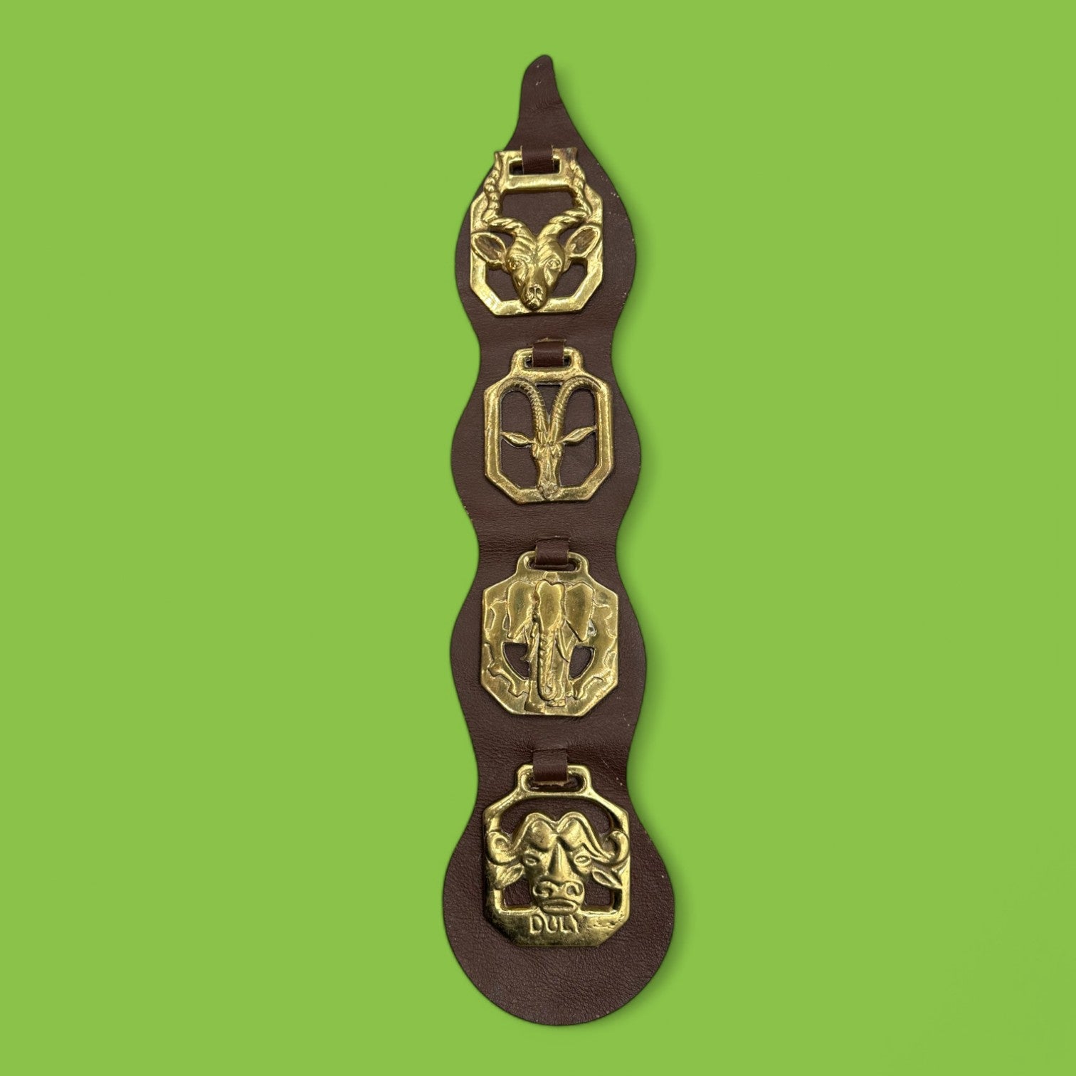 Brass horse decorations on leather strap showcasing African animals like elephants and antelopes. Horse, brass, African animals.