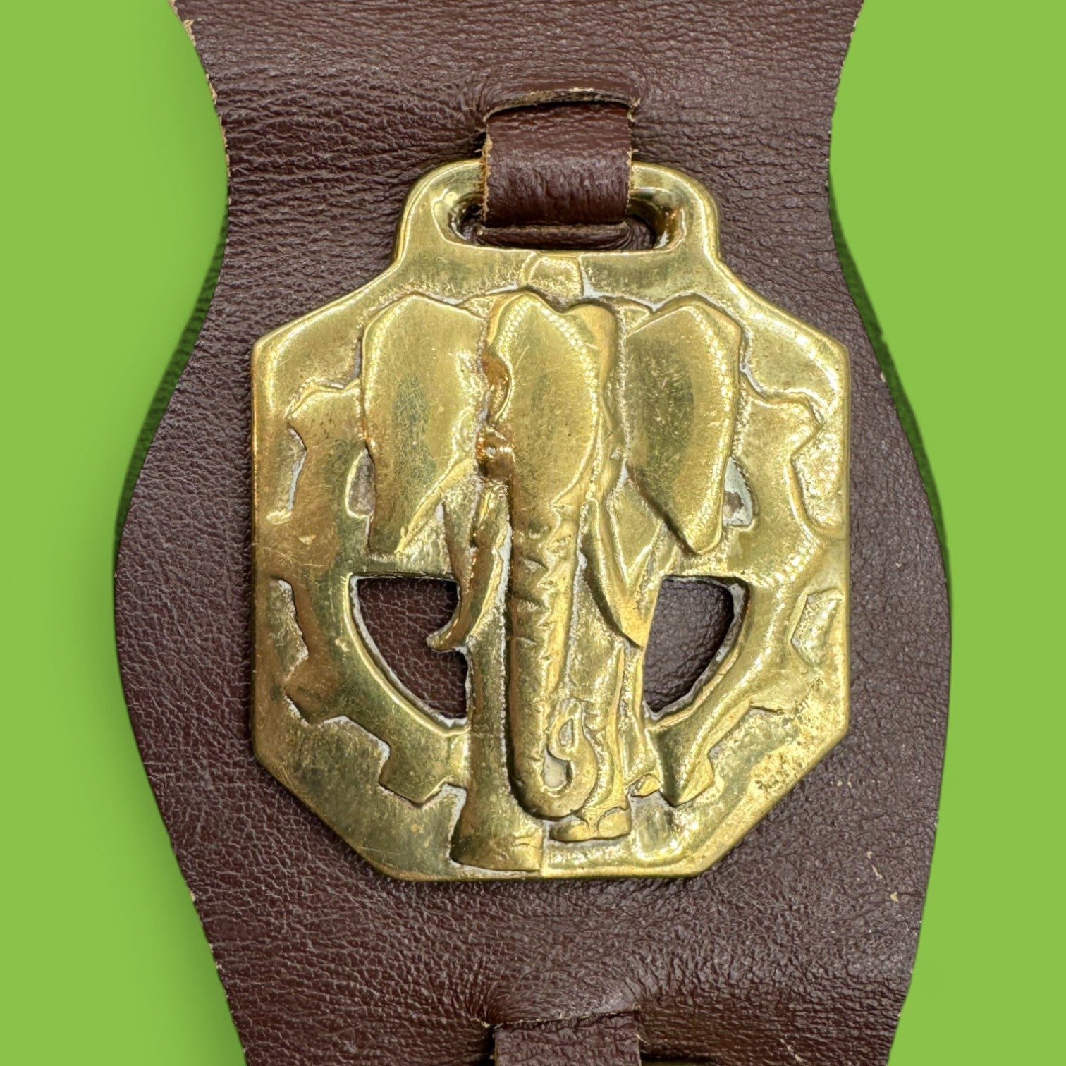 Brass horse ornament on leather strap, featuring African animals like elephants and buffalo. Ideal for collectors.